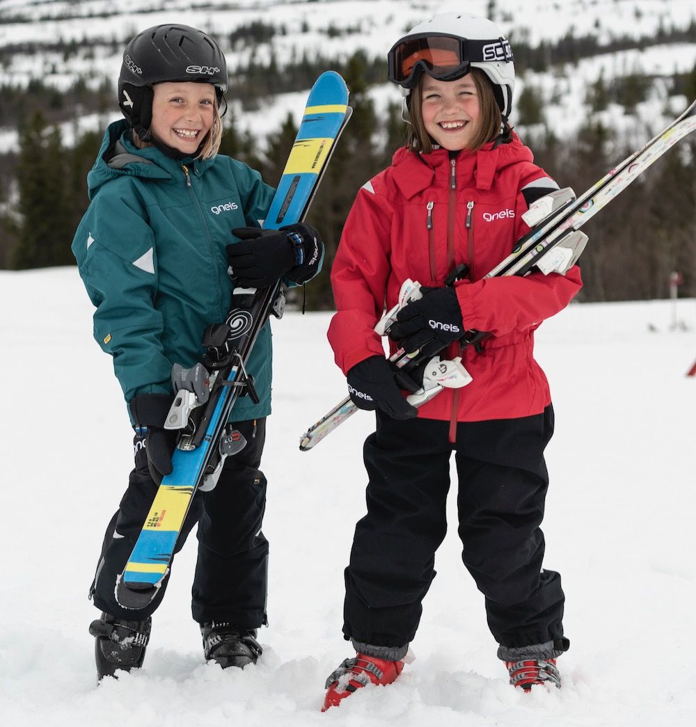 Två barn som bär slalomskidor iklädda Gneis vinterkläder för barn
