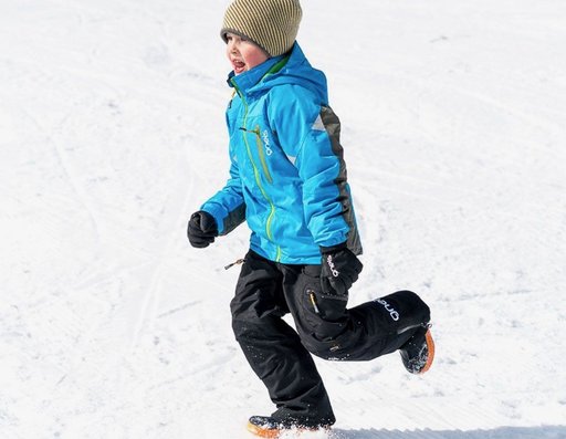 En kille som springer i snön iklädd Supershape vinteroverall från Gneis barnkläder
