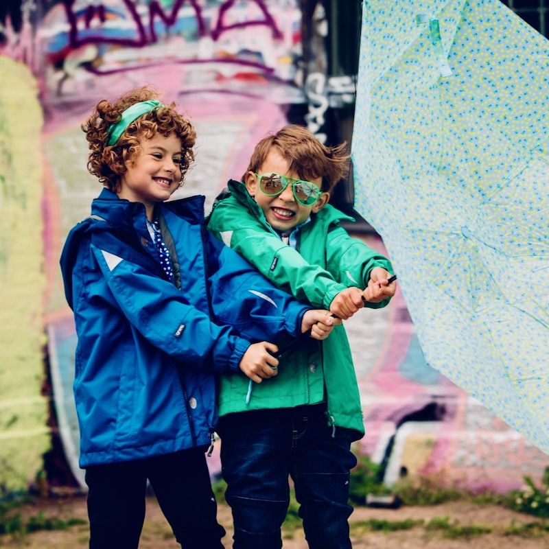 Gneis skaljackor på två barn som leker med ett paraply i vinden.