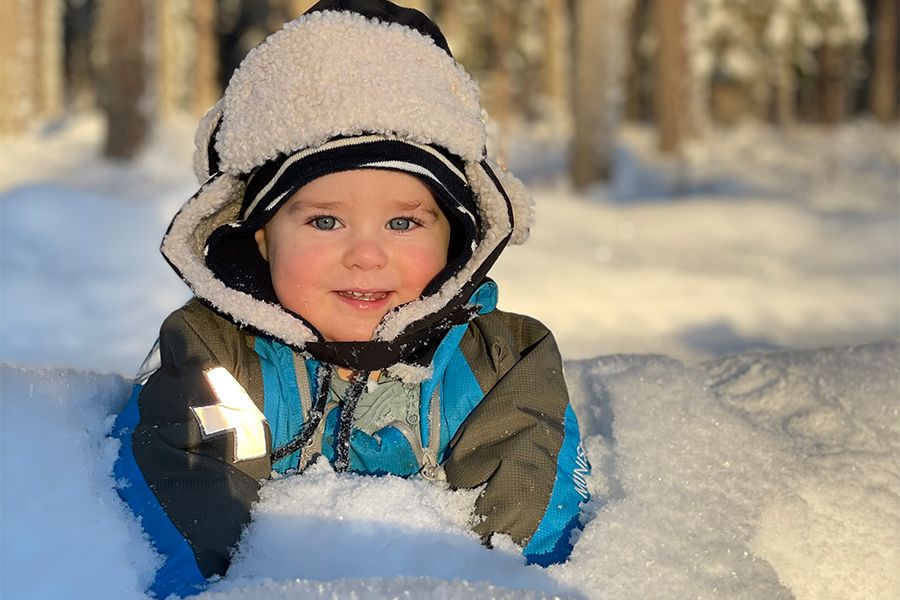 Litet barn leker i snön med Gneis babyoverall
