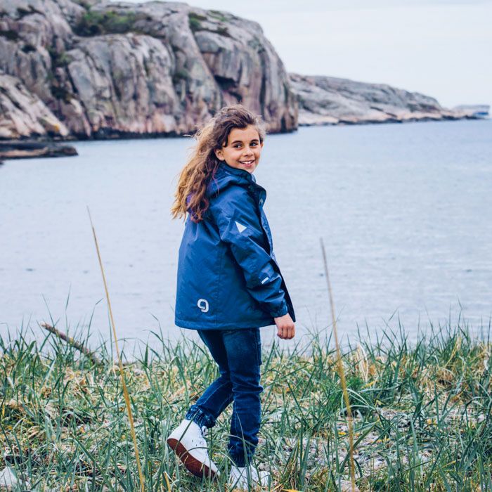 Glad flicka i mörkblå skaljacka från Gneis