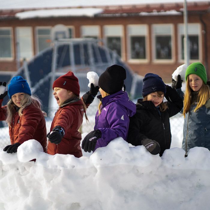 Barn leker snöbollskrig i Gneis skalkläder