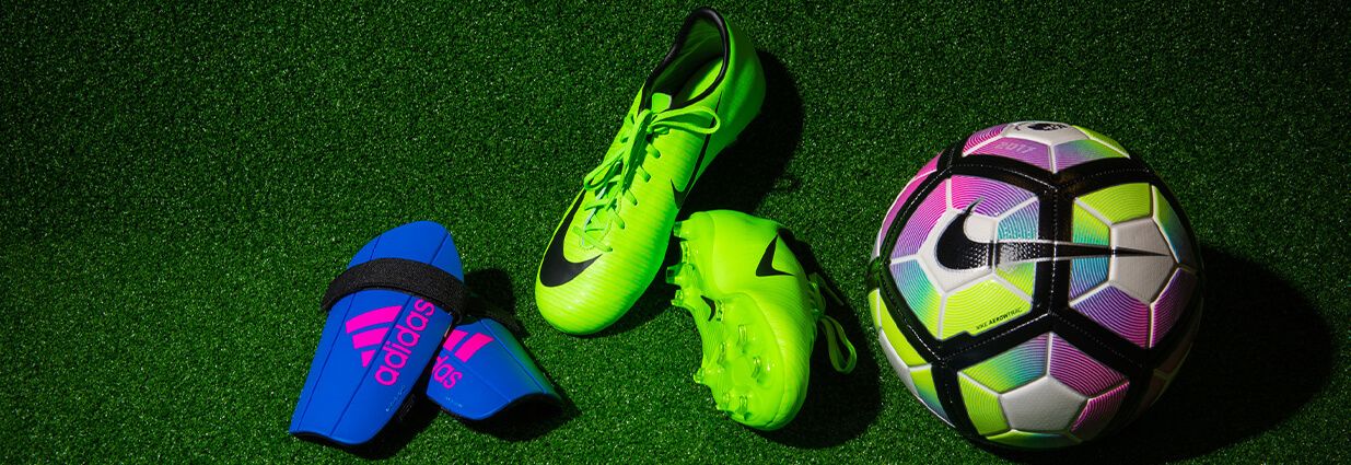 Ett par blåa Adidas benskydd, ett par gröna Nike fotbollsskor och en Nike fotboll