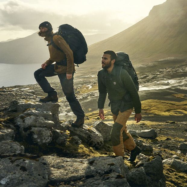 Zwei Männer wandern in Wanderhosen und Outdoor-Jacken an der schwedischen Westküste.