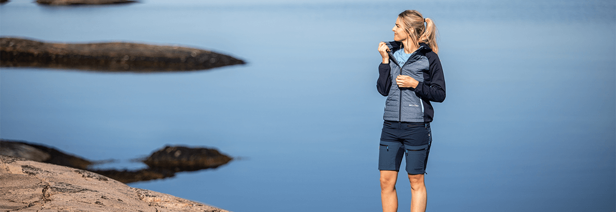 En tjej har på sig en blå jacka och ett par blåa shorts som är ifrån Swedemount med kollektionen Lofoten stretch
