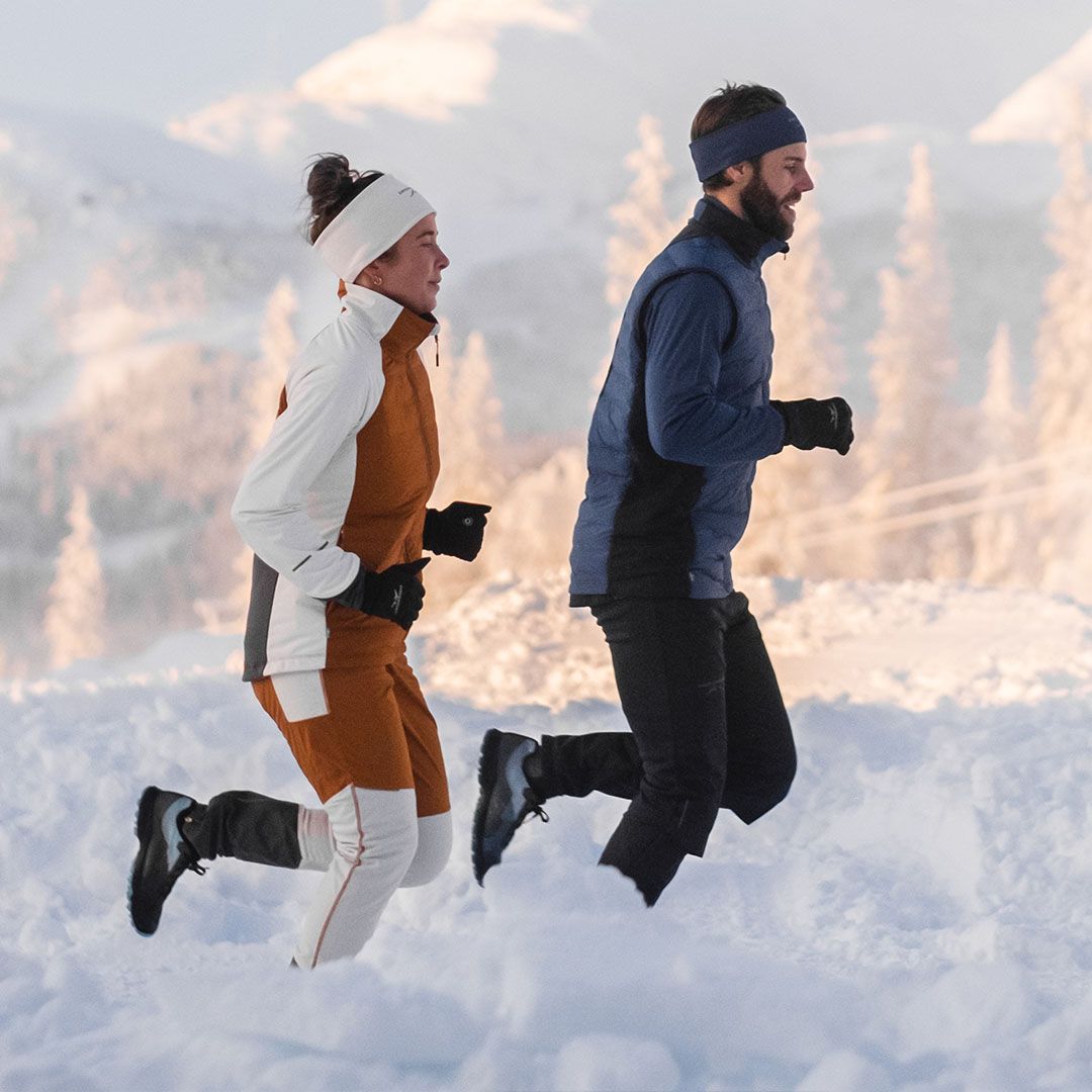 Frau und Mann joggen in gefütterter Laufkleidung durch den Schnee.
